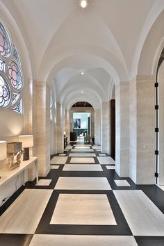 a long hallway with black and white flooring next to a clock on the wall