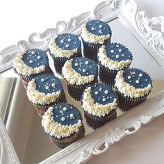 cupcakes with blue frosting and white sprinkles in front of a mirror