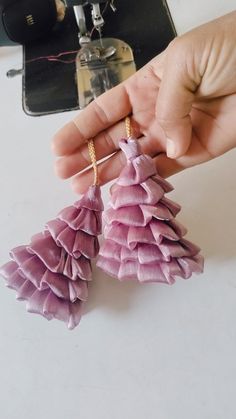 someone is holding two small purple tassels