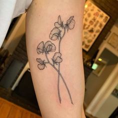 a black and white photo of a flower tattoo on the left arm, with three flowers growing out of it