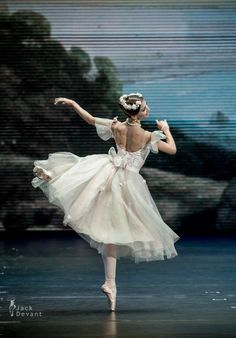 the ballerina is wearing a white dress and has her arms stretched out in front of her