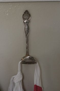 a silver spoon hanging on the wall next to two red and white towels