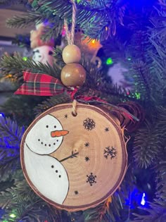 a wooden ornament with a snowman on it hanging from a christmas tree