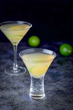 two martini glasses with limes in the background