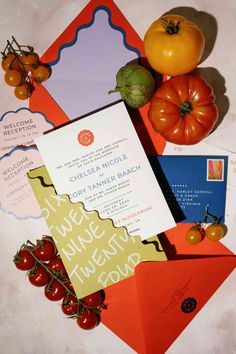 an assortment of different types of wedding stationery on display with tomatoes, peppers and broccoli