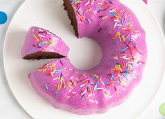 a pink frosted doughnut with sprinkles on a white plate