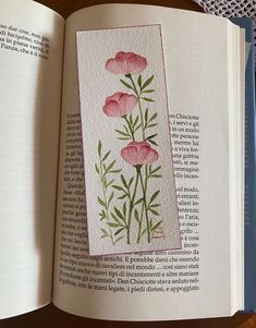 an open book with watercolors on it and some flowers in the middle one