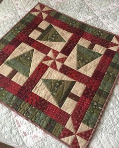 a close up of a quilt on a bed with red, green and white colors