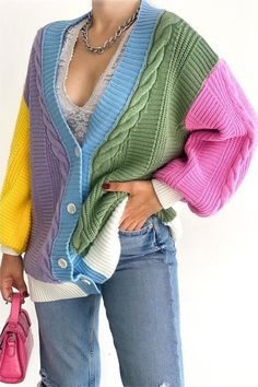 a woman in ripped jeans and a colorful cardigan sweater is holding a pink purse