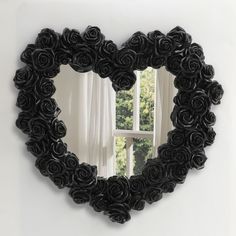 a heart shaped mirror with black roses on the front and sides, hanging from a wall