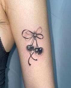 a tattoo on the arm of a woman with two cherries attached to it's sides