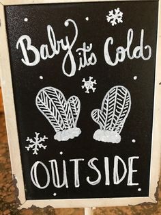 a sign that says baby it's cold outside with snowflakes and mittens