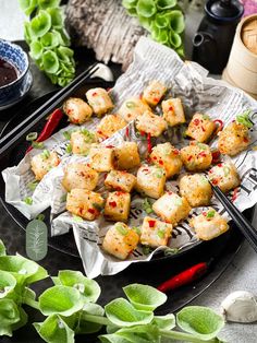 there are some food on the plate with chopsticks next to it and green plants