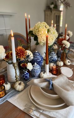 the table is set with blue and white vases, candles, and plates on it