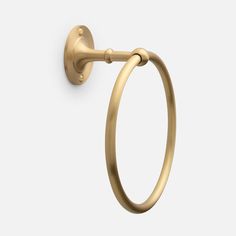 an open brass towel ring on a white wall, with the handle extended to it's left side