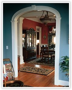 an archway leading into a dining room and living room with blue walls, wood floors and white trim