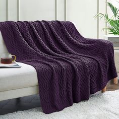 a couch with a purple blanket on it and a cup of coffee in front of it