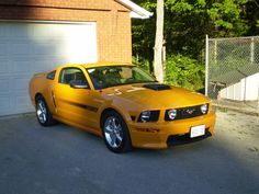 a yellow sports car parked in front of a garage