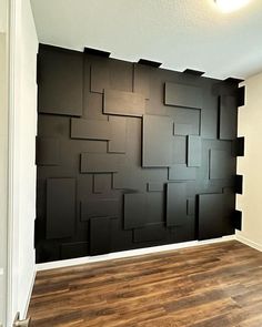 an empty room with wood flooring and black wall