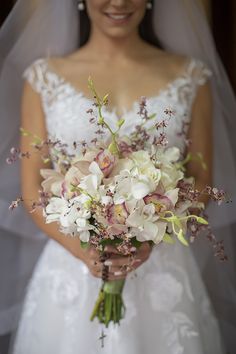 a bride holding a bouquet of white and pink flowers on her wedding day in front of the camera