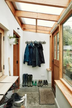 a room with several pairs of shoes hanging on the wall and two coats hung up to dry