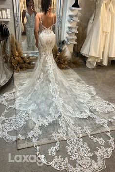 a woman looking at her wedding dress in front of a mirror with other dresses on display