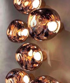 several shiny balls are hanging on the wall with light bulbs attached to each one in front of them