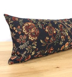 a black and red floral pillow on top of a wooden table