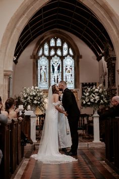 a bride and groom kissing in front of the alter