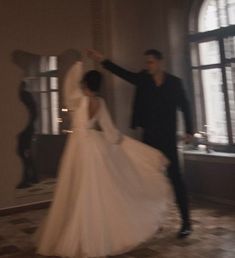 a bride and groom are dancing in an elegant room with large windows on either side