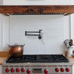 a stove top oven sitting inside of a kitchen next to a wall mounted pot rack