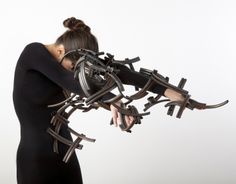 a woman in black dress holding several metal objects