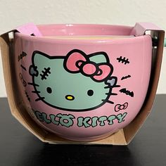 a pink hello kitty coffee cup sitting on top of a table