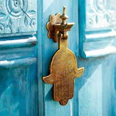 an ornate brass door handle on a blue wooden door