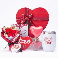 a valentine's day gift box with two heart shaped boxes, a mug and some candy