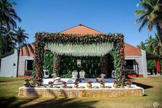 an outdoor wedding setup with flowers and greenery on the table, surrounded by palm trees