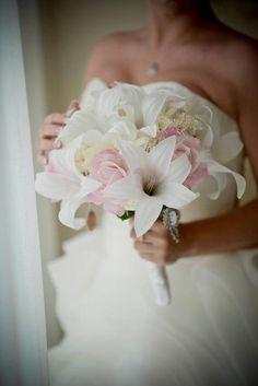 a woman holding a bouquet of flowers in her hand while standing next to a wall