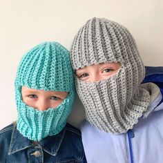 two children wearing knitted hats and scarves, one with a face mask on