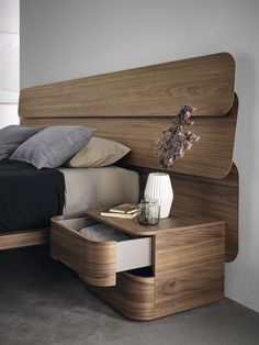 a bed with a wooden headboard and night stand next to it on concrete flooring