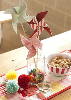 a glass vase filled with candy and pinwheels on top of a wooden table