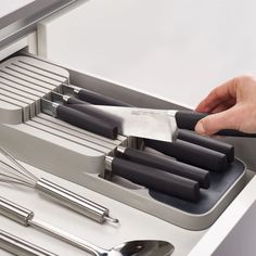 a person holding a knife and some utensils in a drawer with silverware