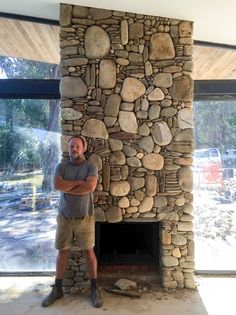 a man standing in front of a stone fireplace