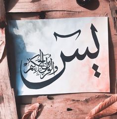 an arabic calligraphy is displayed on a piece of paper next to some other items