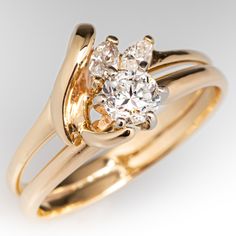 a yellow gold engagement ring with an oval diamond in the center and two smaller round diamonds on each side