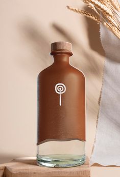 a brown glass bottle sitting on top of a wooden table next to a wheat stalk