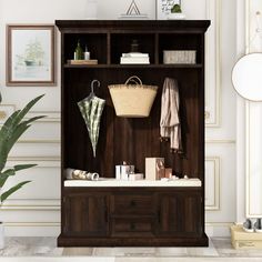 a wooden cabinet with an umbrella and other items on it in a white room next to a potted plant