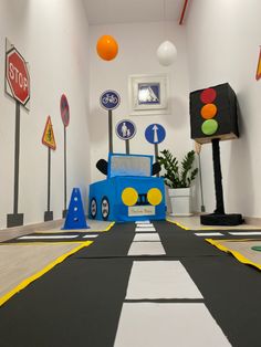 a toy truck driving down a road with traffic lights on either side and street signs hanging from the ceiling