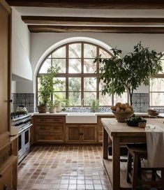 a kitchen with an arched window and tile flooring, potted plant on the counter