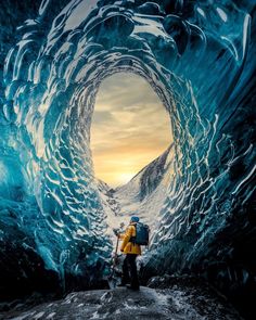 a man with a backpack standing in an ice cave