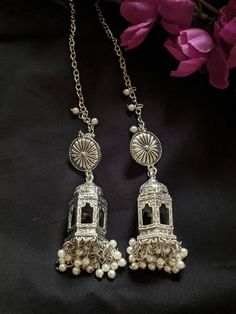 Add charm and charisma to your beautiful personality with these exquisitely designed and handcrafted Radha Krishna inscribed jhumkas lined with fine pearls Pair them up with any casual or semi formal attire and gather compliments all the way. The earrings are light weight so can be worn comfortably even for longer hours. The unique design will surely make you a head turner! Each earring weighs 24 GM's Drop length 3 inches approx Length of the ear chain 5 inches approx Note: All in stock items wi Silver Oxidized Temple Jewelry Jhumkas, Oxidized Temple Jewelry Dangle Earrings, Dual-tone Metal Jhumkas In Temple Jewelry Style, Oxidized Temple Jewelry Earrings For Festivals, Traditional Oxidized Dangle Jhumkas, Beautiful Personality, Semi Formal Attire, Ear Chain, Traditional Earrings